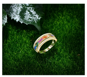 Vue macro d'une bague dorée avec pierres arc-en-ciel sur un fond de mousse verte