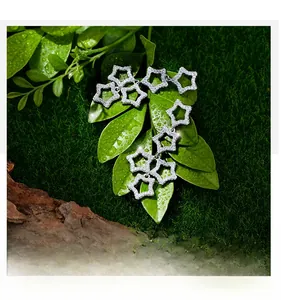 Macro shot of silver five-point star drop earrings with micro-paved white zircons on moss