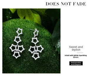 Detail of silver star earrings with pave white zircons on natural moss background