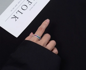 Gros plan d'une bague en argent S925 avec pierres arc-en-ciel colorées au doigt