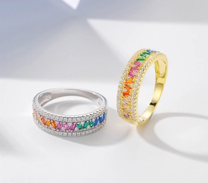 Close-up of rainbow baguette crystals and pavé diamonds on gold and silver rings