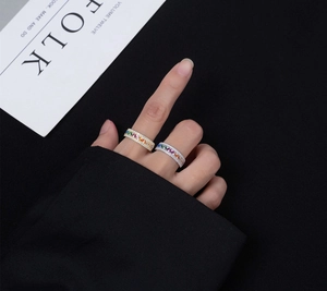 Macro detail of rainbow gemstone eternity rings with pavé diamonds on a model's hand