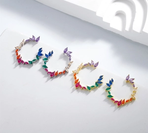 Detail of gold and silver olive branch earrings with colorful marquise-cut zircons