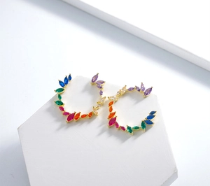 Macro detail of rainbow marquise-cut gems set in gold-plated olive branch earrings