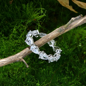Pear-cut 925 sterling silver eternity ring displayed on wood with moss background