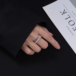 Detailed view of silver band set with rainbow colored zircons on model finger