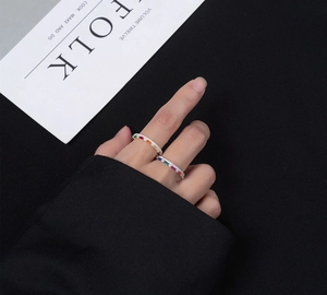 Close-up of two stacked gold rings with colorful rainbow gemstones on black fabric