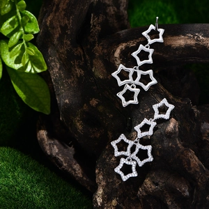 Star-shaped sterling silver drop earrings with micro-pave crystals on wooden background