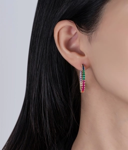 Close-up of rainbow cubic zirconia gold hoop earrings worn on a model's ear