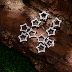 Star-shaped long drop earrings with micro-paved rhinestones on a natural mossy bark background