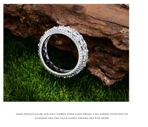 Vue macro d'une bague éternité en argent avec pierres marquises sur mousse et bois