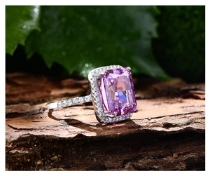 Détail d'une bague avec gemme violette de 13 carats sur une feuille avec gouttes d'eau