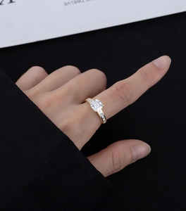 Close-up of gold-plated silver ring with Asscher cut diamond and side stones on finger