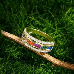 Bague ondulée dorée sertie de pierres arc-en-ciel et diamants sur fond mousse