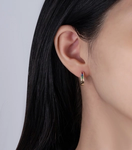 Close-up of gold huggie earrings with rainbow baguette-cut stones in channel setting