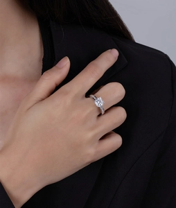 Close-up of Asscher cut square diamond ring worn on hand with silver finish and side stones