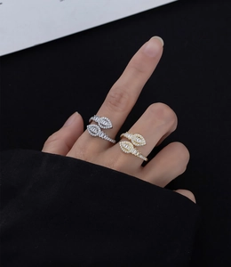 Detail of gold and silver leaf-shaped wrap rings with pavé diamonds on a model's hand