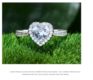 Dettaglio di un anello a cuore in argento sterling S925 con diamanti su un prato verde