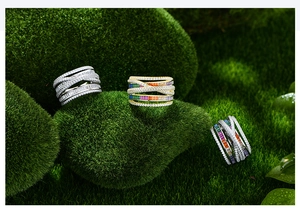 Detailed view of criss-cross pave rings with colorful gemstones on natural moss rocks