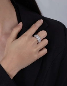 Detailed view of wide silver ring with square geometric pattern worn with black suit