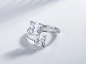 Détail macro d'une bague bypass en argent avec deux pierres carrées et diamants baguettes
