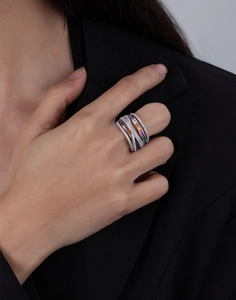 Detailed view of a wide silver ring with rainbow gemstones worn by a model in a black suit