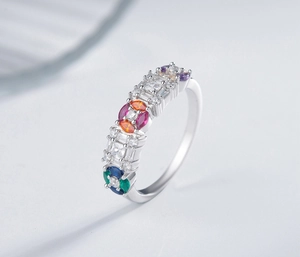 Detail view of colorful gemstones in various shapes set on a polished silver ring band