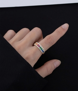 Vista macro di un anello dorato con pietre a goccia arcobaleno e pavé di diamanti
