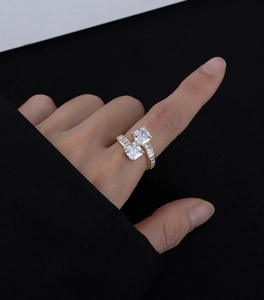 Détail de la bague ouverte dorée avec zircons blancs carrés et pierres latérales sur la main