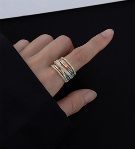 Close-up of a multi-layer gold band ring with pavé diamonds and rainbow gemstones