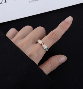 Close-up of gold-plated ring with colorful emerald and oval cut cubic zirconia gems