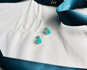 Macro shot of 925 silver pear-cut emerald earrings surrounded by small cubic zirconia