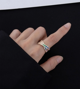 Close-up of golden crisscross ring featuring rainbow baguette stones and micro pavé cz
