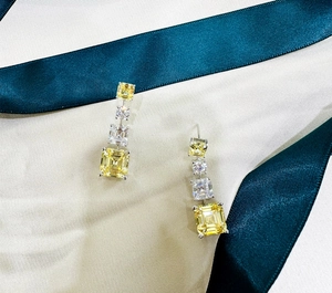 Gros plan de longues boucles d'oreilles en argent avec cristaux carrés jaunes et blancs