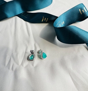 Macro view of pear-cut emerald earrings in 925 silver with blue stones on silk ribbon