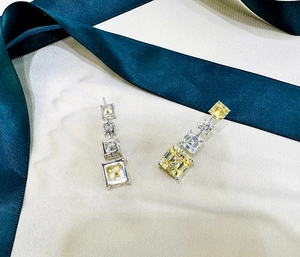 Détail de boucles d'oreilles longues en argent avec cristaux carrés jaunes et blancs