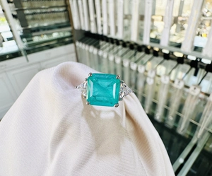 Detailed macro view of 10x10mm emerald-cut emerald ring with triangular side stones