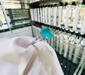 Macro view of emerald cut teal gemstone ring with trillion side stones on 925 silver band