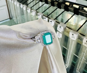 Detailed macro view of an emerald-cut green gemstone ring with side trapezoid diamonds