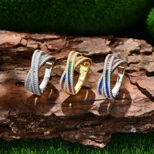 Three crisscross S925 silver rings with colorful rainbow gemstones on natural mossy bark