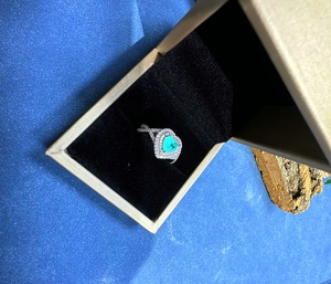 Macro detail of heart-cut Paraiba gemstone ring with halo diamonds in luxury jewelry box
