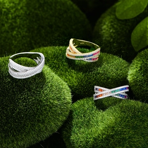 Crossed S925 silver rings with rainbow gemstones and pavé zircon on moss background
