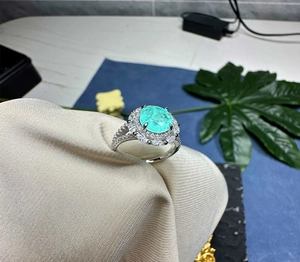 Macro detail of oval mint green gemstone ring with double-layered halo of zircon crystals