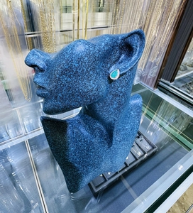Detail view of pear-shaped emerald earrings with pavé zircons on model ear