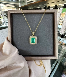 Detail of 8x10mm emerald pendant necklace with double halo diamonds in 18k gold finish