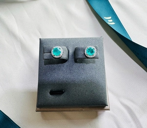 Macro shot of 925 silver stud earrings with blue gemstone and halo of white zircons