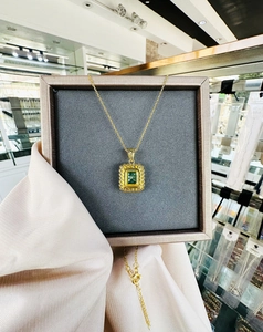 Close-up of a vintage 18k gold plated necklace with a rectangular emerald green gemstone