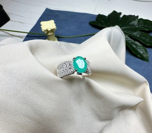Vue macro d'une bague avec pierre précieuse ovale verte et diamants pavés sur argent