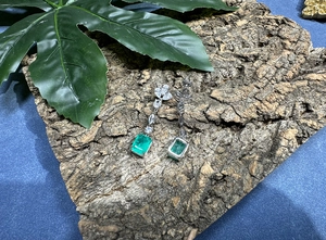 Detailed view of 8x10mm emerald cut drop earrings on rustic bark background