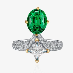 Macro detail of oval emerald ring with yellow gold prongs and diamond halo band